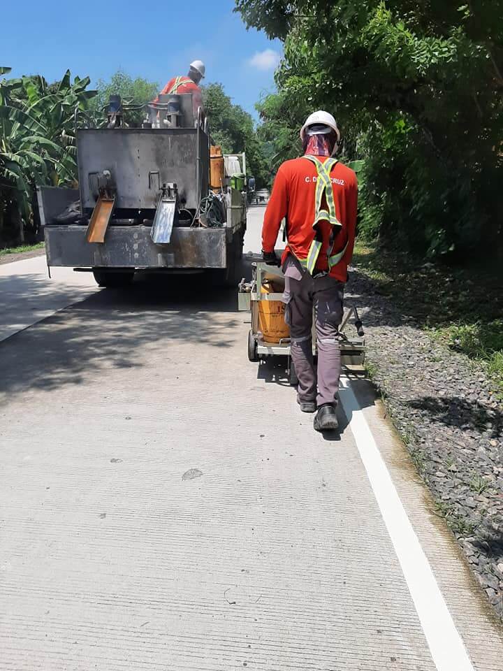 Road contractor applying white road marking paint