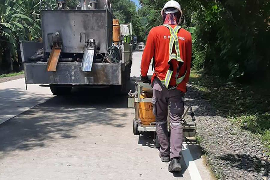 Road contractor applying white road marking paint