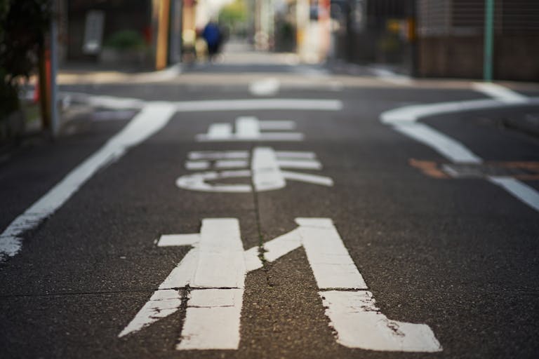 A close-up view of a Japanese city street with white painted markings in Nagoya, Japan.